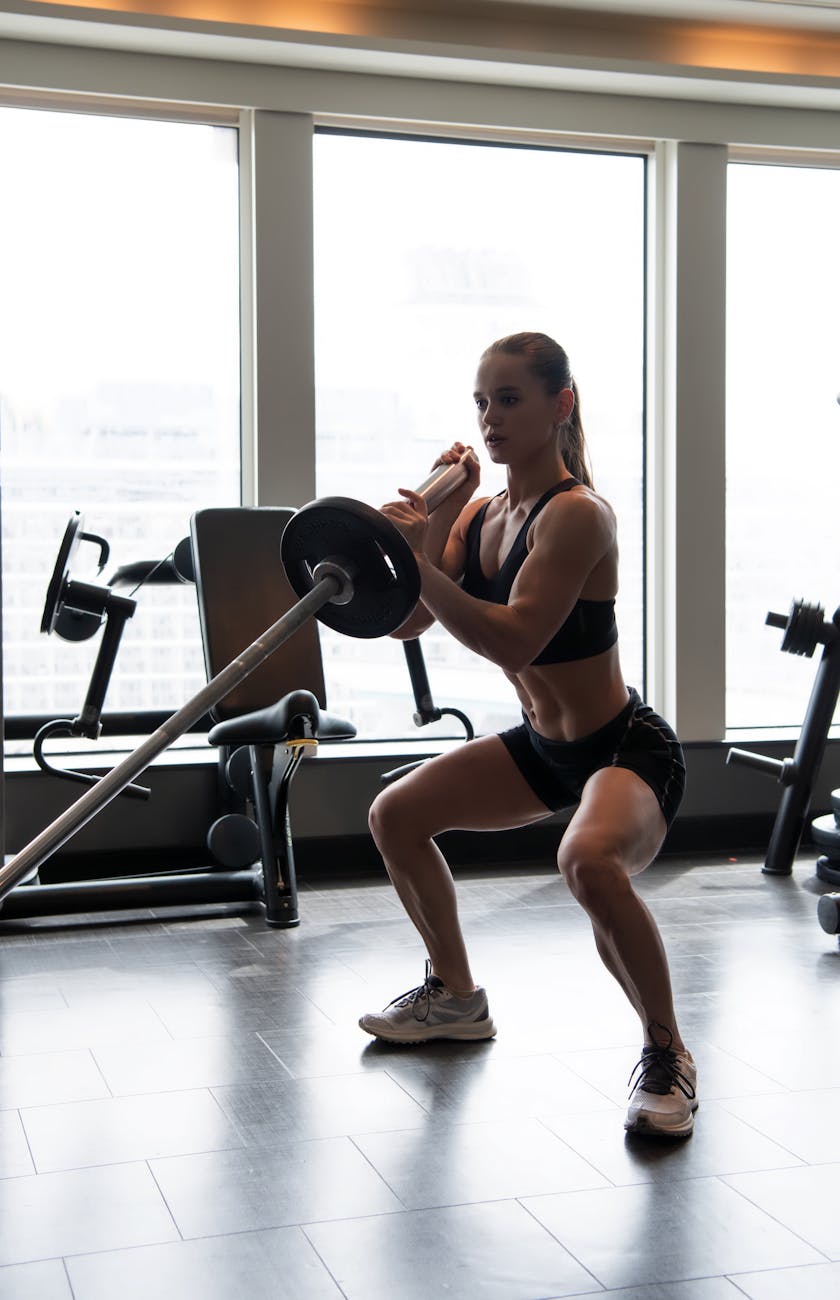 female athlete performing barbell squats in gym