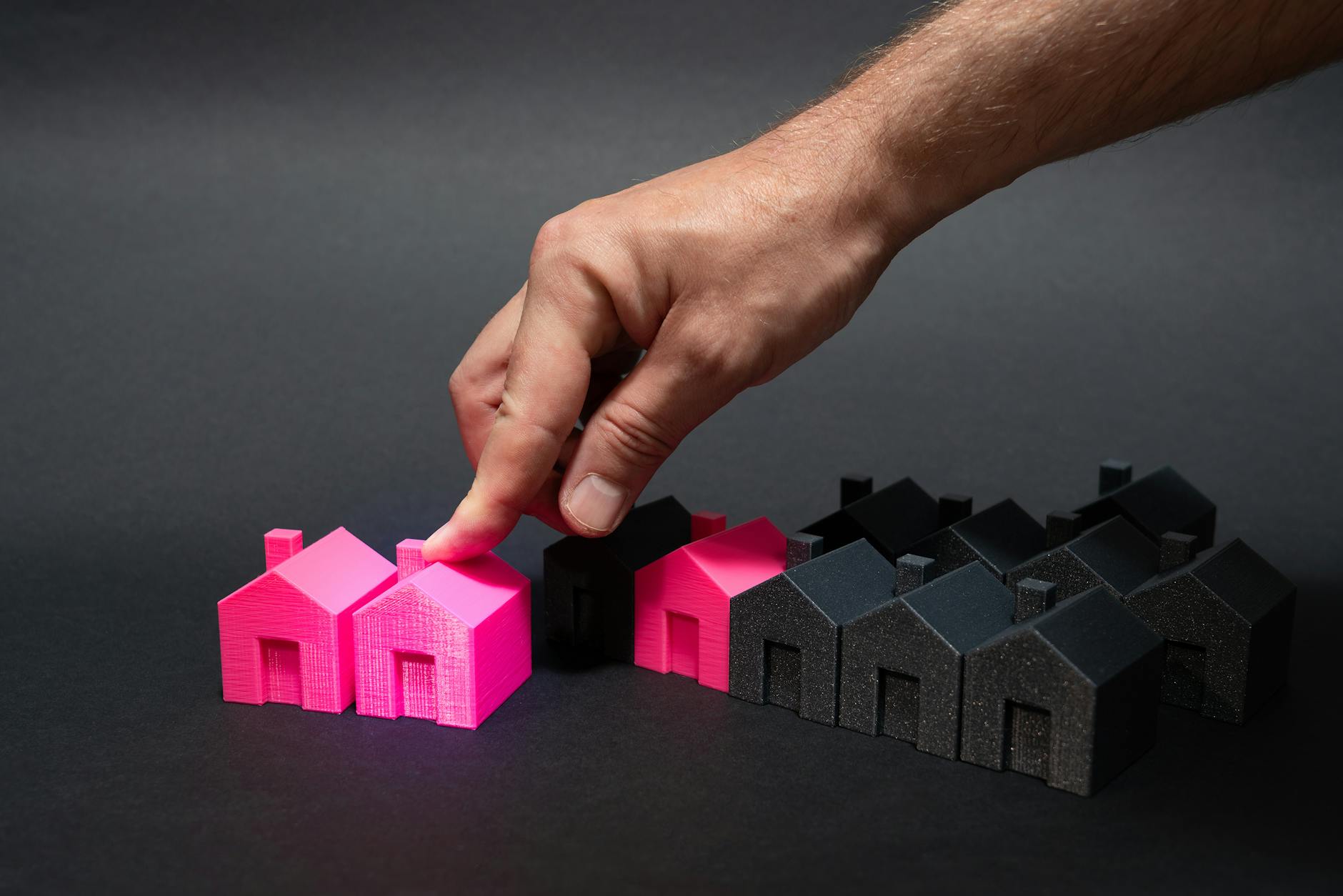 hand selecting pink house model for real estate choice