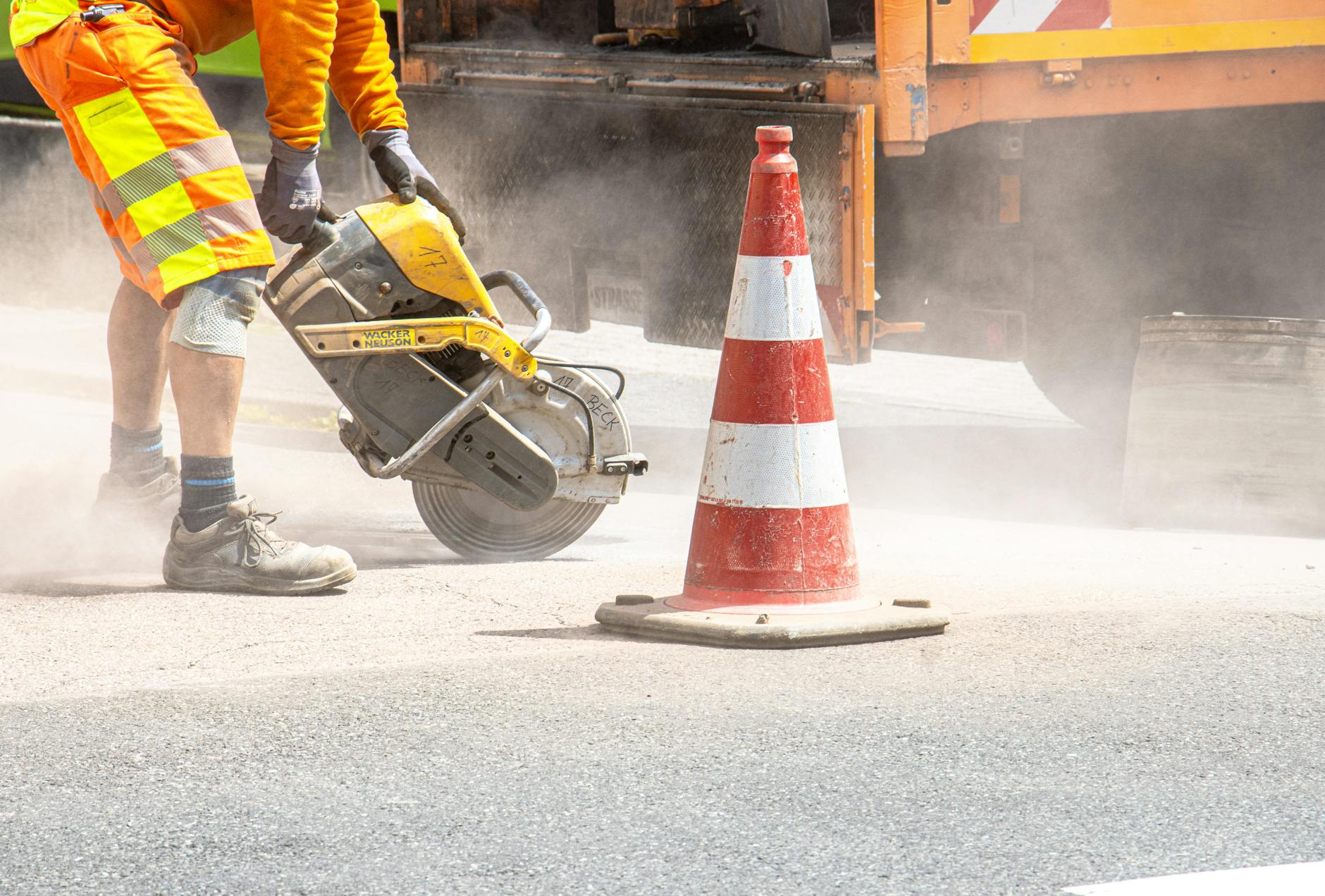 road construction worker cutting asphalt with saw