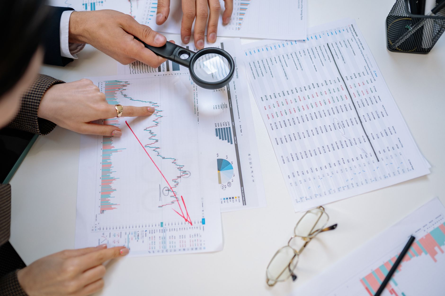 people hands around charts on table